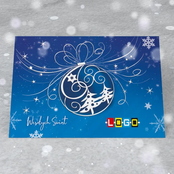 Bombka rysowana białą kreską pod kokardą, w środku spirale, księżyc i choinki, tło od błękitu do granatu
