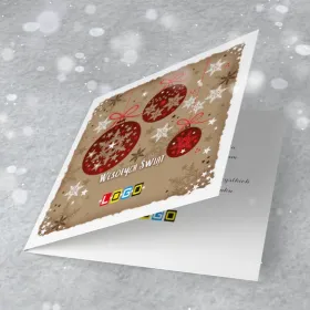 Trzy bordowe bombki ze śnieżynkami na beżowym papierze kraft, z czerwonymi nitkami i białymi gwiazdkami