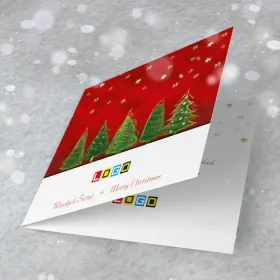 Rząd zielonych choinek na czerwonym tle z białymi gwiazdkami, niżej na białej belce logo i napis „Merry Christmas”