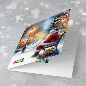 Postać w czerwonym ubraniu na ławce wśród ośnieżonych drzew, latarni, lampek i ozdób, w niebieskiej scenerii