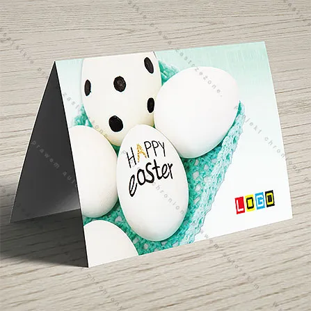 Białe jaja, jedno w czarne kropki, w koszyczku z turkusowej włóczki na miętowym tle, na jajku odręczny napis Happy Easter