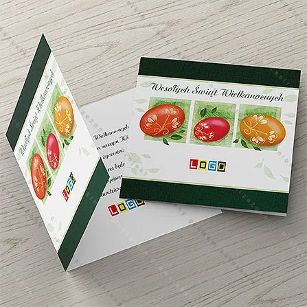 Trzy pisanki w czerwieni, karminie i pomarańczu w kwadratowych zielonych ramkach między ciemnozielonymi pasami na bieli