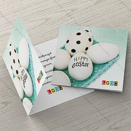 Białe jajka w koszyczku z turkusowej nitki, na największym czarny napis HAPPY easter, na drugim kropki