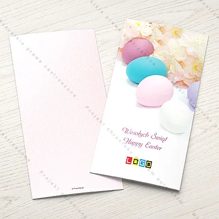 Białe jajka na turkusowej serwetce z szydełka na miętowym tle, na środkowym odręczny napis „HAPPY easter”