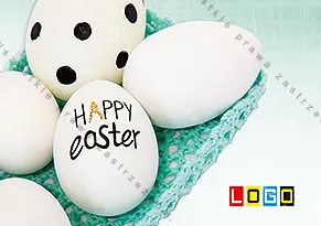 Widok z góry na białe jaja w turkusowym kartonie, na największym czarny napis „HAPPY Easter” odręcznym pismem